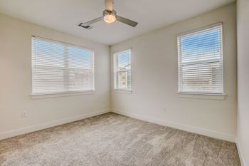 A room with a carpeted floor, a ceiling fan, and two windows with blinds. at Aurora Watson Branch, Texas